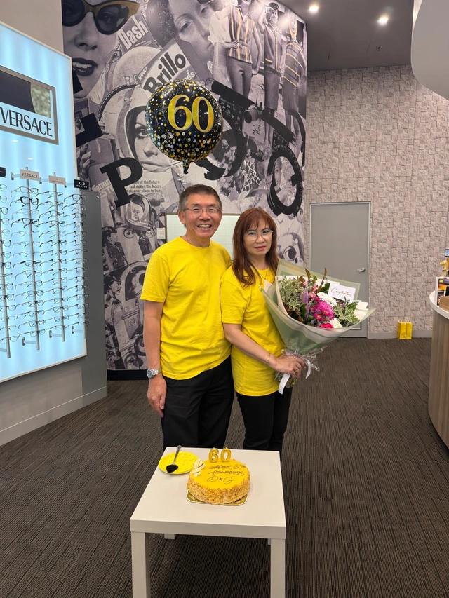 Andrew and Helen Sng with flowers and an anniversary cake, celebrating 60 years of Dannell and Gollop